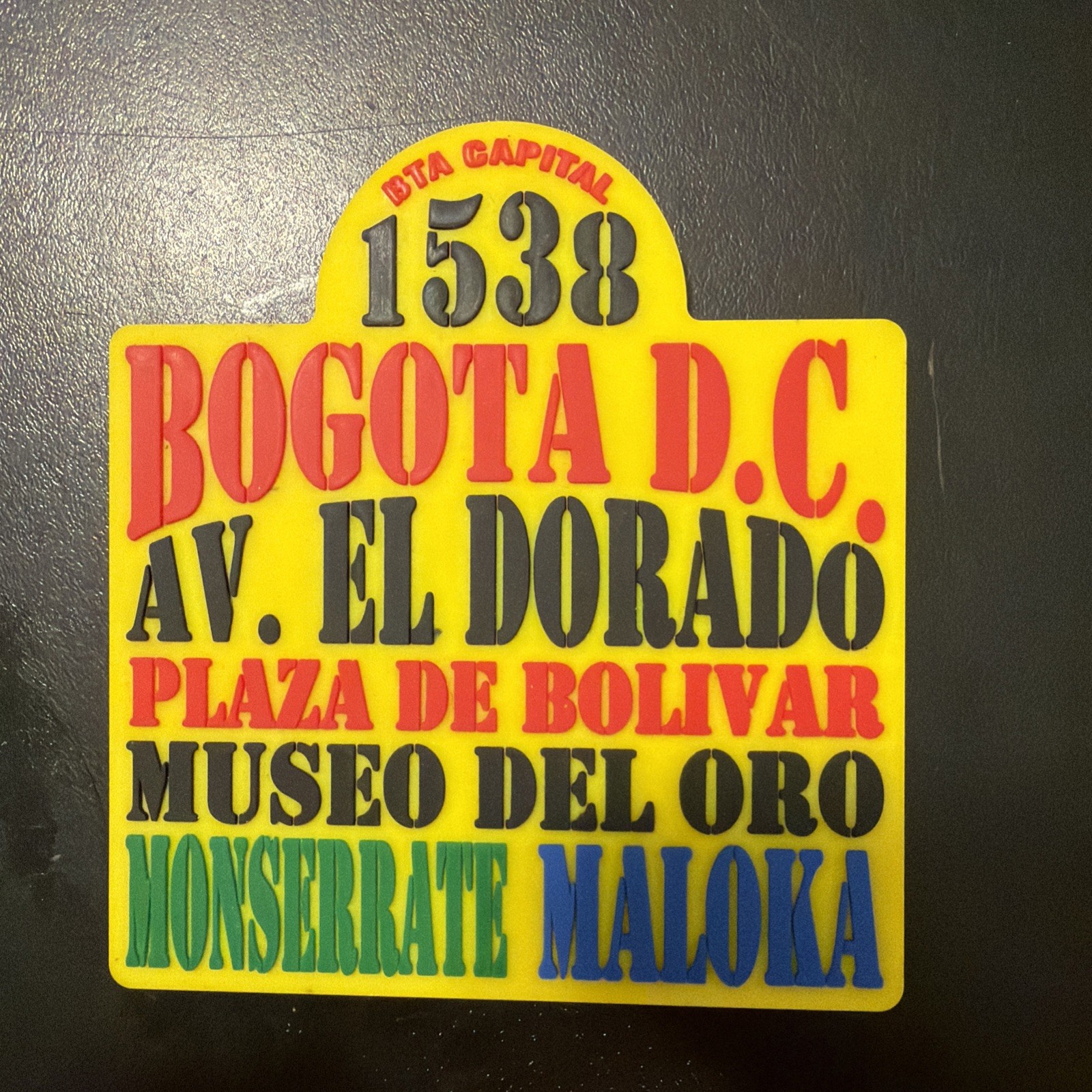 souvenir pin or coaster designed to look like a vintage Bogotá bus route sign,