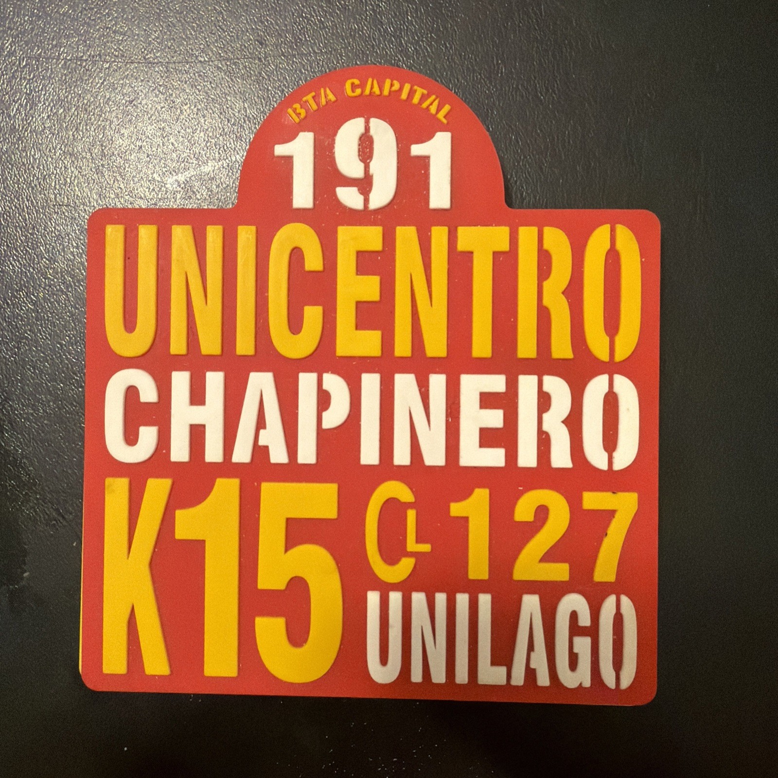 souvenir pin or coaster designed to look like a vintage Bogotá bus route sign,